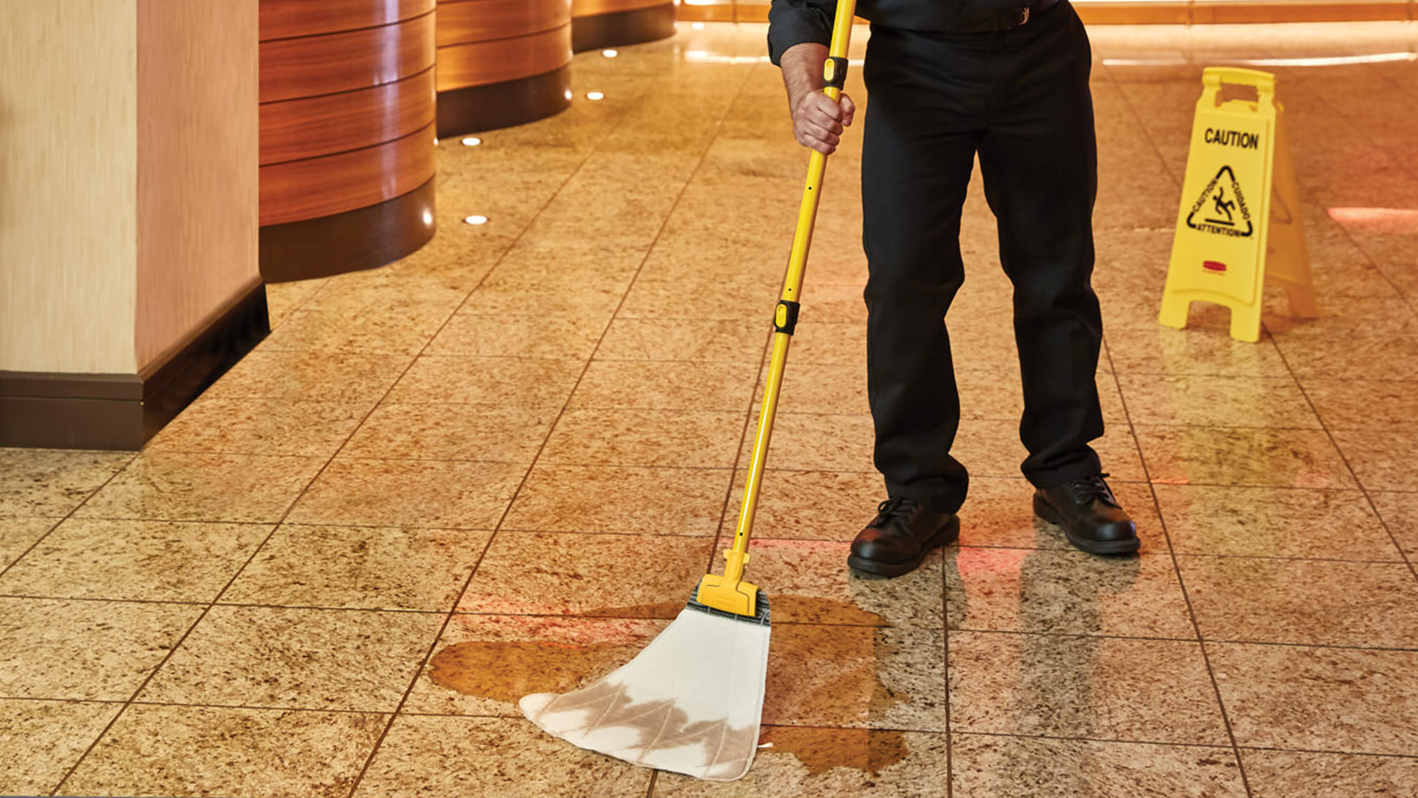 Man using a Rubbermaid Commercial High Absorbency Spill Mop in cleaning a hotel floor