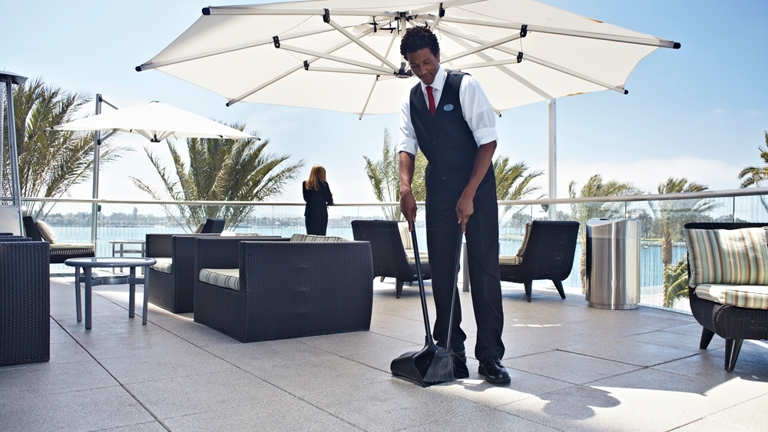 A hotel staff cleaning the rooftop lounge using an Executive Series™ Lobby Pro® Dustpan With Cover