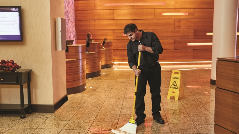 A cleaner sweeping a hotel floor lobby using HYGEN™ PUlSE™ Microfibre Mop Kit