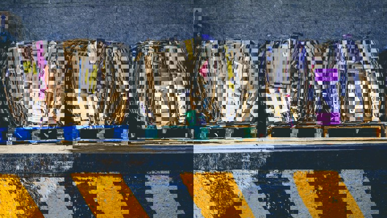 Three large bales of compressed cardboard and paper sit on blue wooden pallets.
